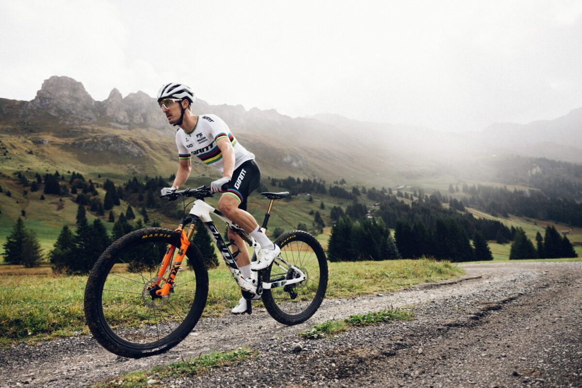 Mountainbikerin auf einem Schotterweg vor einer Bergkette