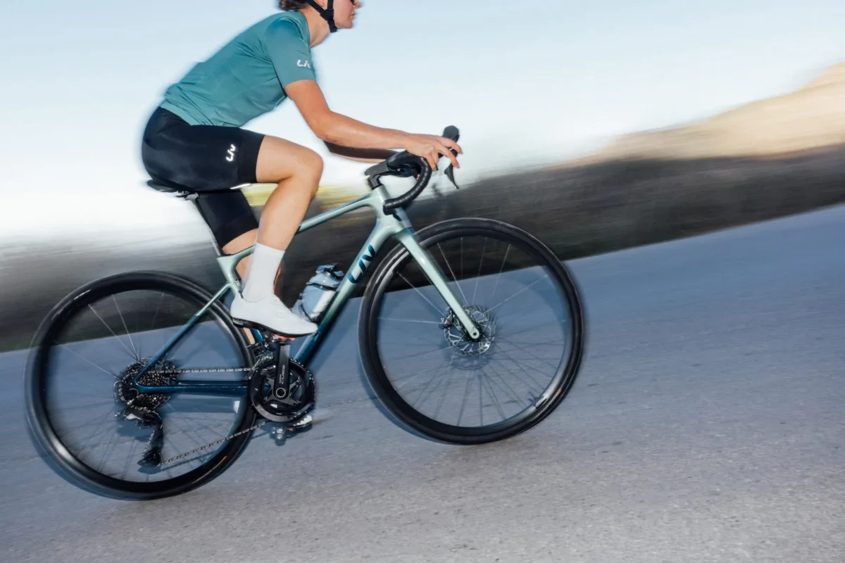Radfahrerin auf einem mintfarbenen Liv Rennrad auf glattem Asphalt in Fahrt