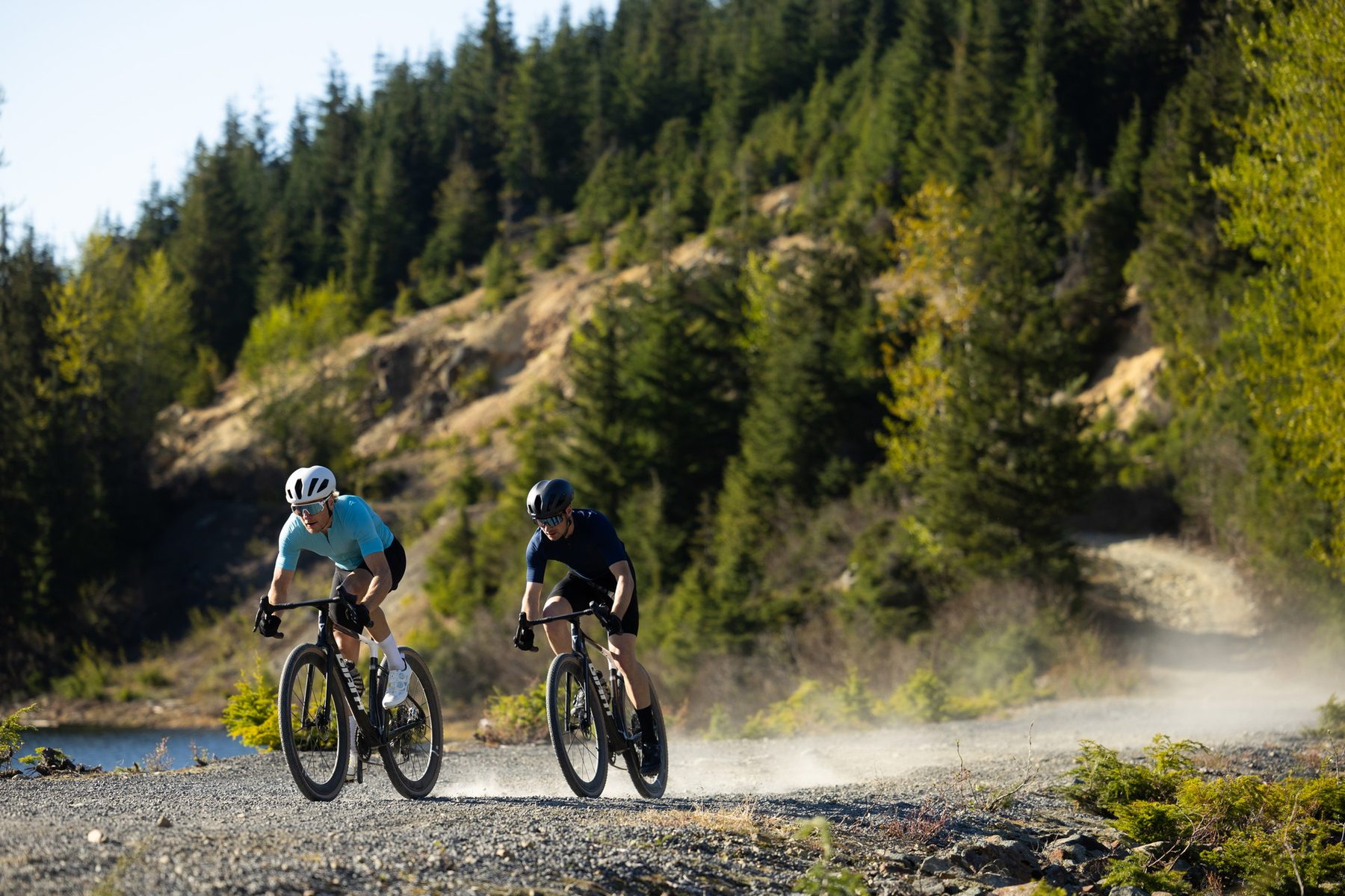 Zwei Radfahrer auf Giant Gravelbikes auf einem staubigen Weg entlang eines Sees